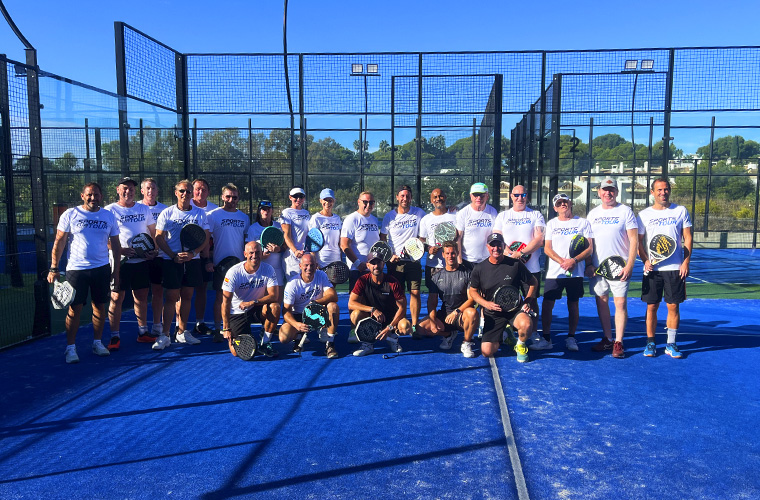 Stor gruppe af padelspillere ved padelbanen i position til billedet i slutningen af padellejren i Marbella