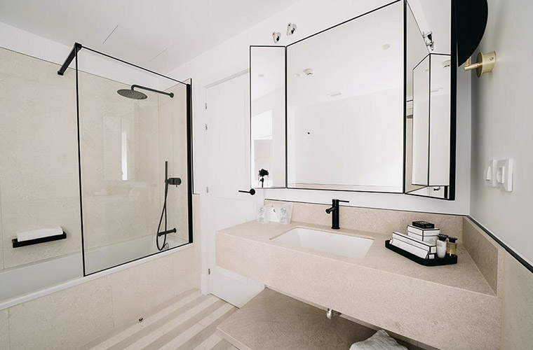 Baño moderno de hotel con ducha, espejo grande y artículos de aseo de primera calidad para los huéspedes del Weekend Padel Camp Málaga
