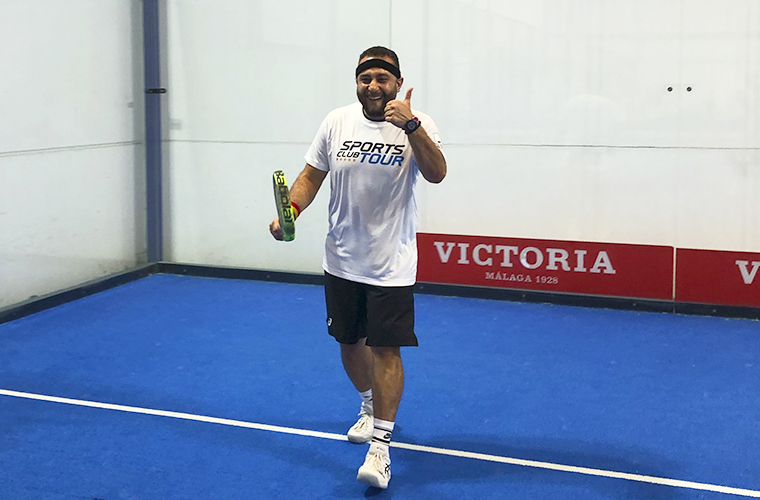 Jugador de pádel en el campamento de pádel de Málaga, en pista azul, vistiendo la camiseta del Sports Club Tour y haciendo el gesto de aprobación con el pulgar.