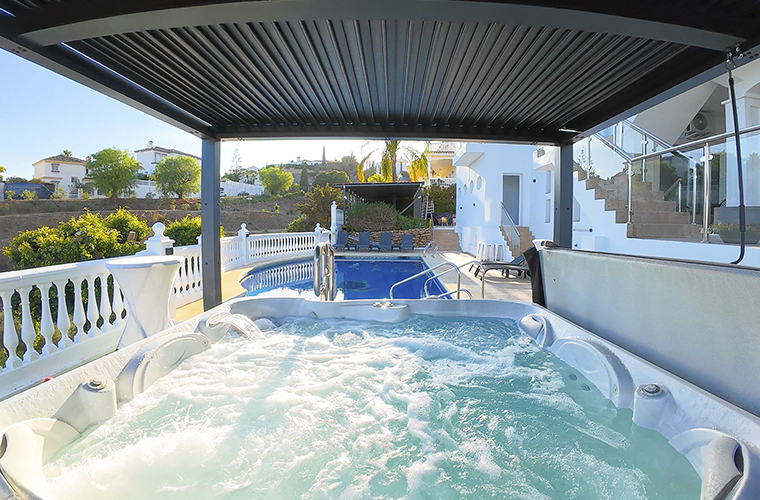 Jacuzzi al aire libre en una villa de lujo en Málaga, con vistas a una piscina privada y rodeado de un entorno natural tranquilo.