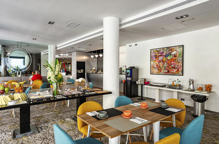 Breakfast buffet area at Mariposa Hotel Malaga with colorful chairs and food stations, official hotel for Weekend Padel Camp Malaga