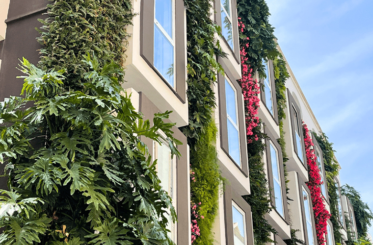 Vertical garden facade of Mariposa Hotel Malaga with lush green and pink plants climbing around the windows