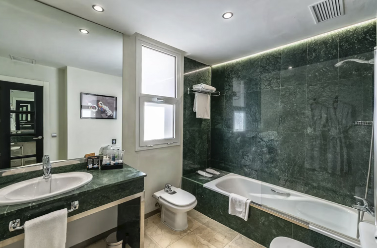 Modern bathroom at Mariposa Hotel Malaga with green marble walls, bathtub, and spacious vanity